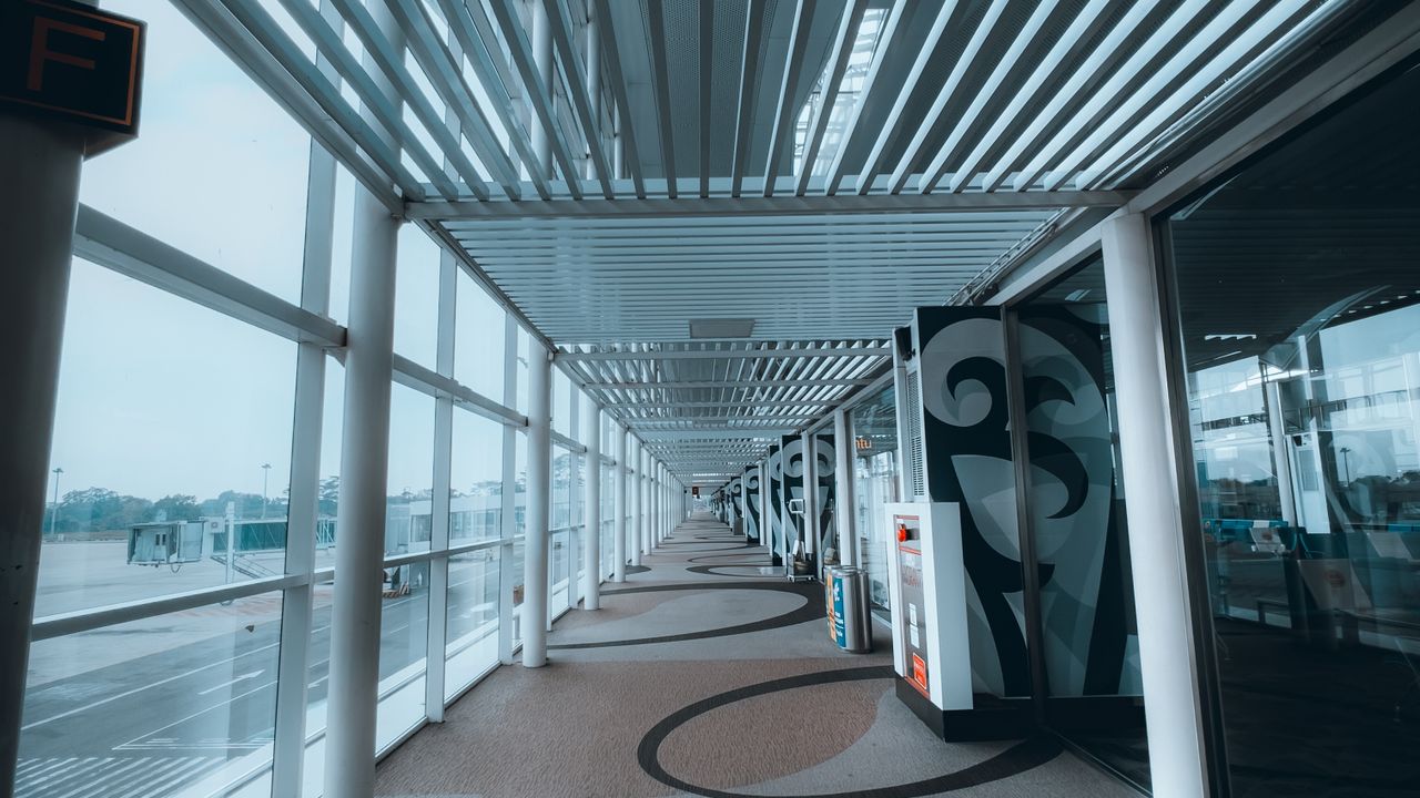 An empty terminal walkway beside floor-to-ceiling windows looking onto the apron